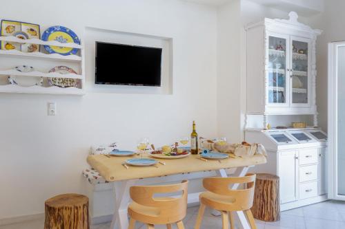 a white kitchen with a wooden table and chairs at Ma mer in Naxos Chora