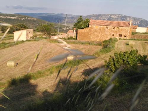 um edifício antigo num campo com uma casa em Masia Campos Culla em Culla