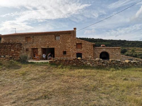 una casa de piedra con gente sentada fuera de ella en Masia Campos Culla, en Culla