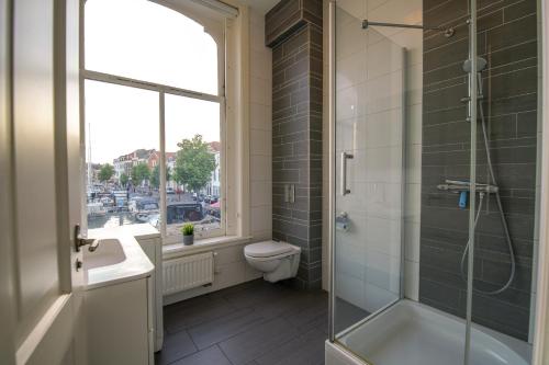 La salle de bains est pourvue d'une douche, de toilettes et d'une fenêtre. dans l'établissement 2L De Volharding, à Leyde