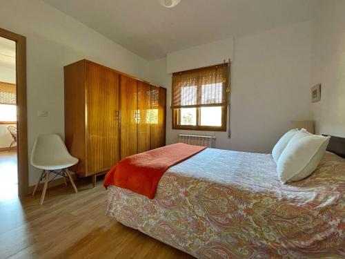 1 dormitorio con 1 cama y 1 silla en ENTRETOXOS en Ribadavia