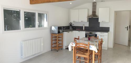 a kitchen with a table and a stove top oven at Loue joli T2,neuf, de 50m2, dans un cadre paisible in Saint-Gervais-dʼAuvergne