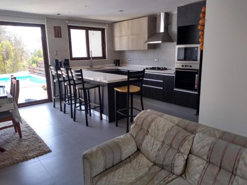 een woonkamer met een bank en een keuken bij Casa Pingueral Tomé in Concepción