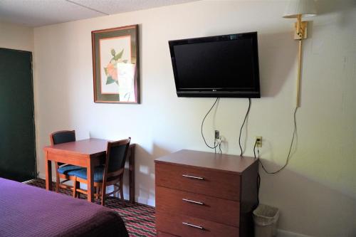 Habitación de hotel con escritorio y TV en la pared en Quality Quarters Inn, en Richmond