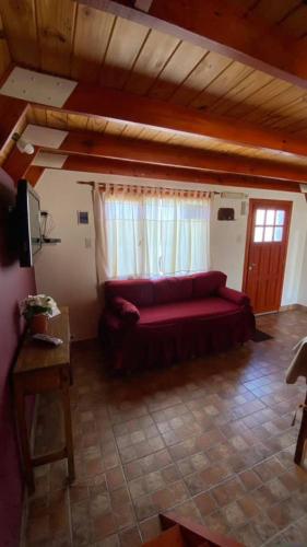 a living room with a red couch and a window at Cabañas del Rosario in Puerto Santa Cruz