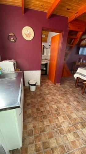 a kitchen with purple walls and a tile floor at Cabañas del Rosario in Puerto Santa Cruz