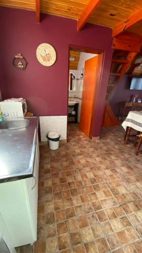 cocina con paredes de color púrpura y suelo de baldosa en Cabañas del Rosario en Puerto Santa Cruz