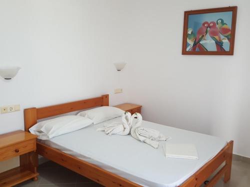 un letto con lenzuola bianche e una foto sul muro di O Fotis ad Agios Prokopios