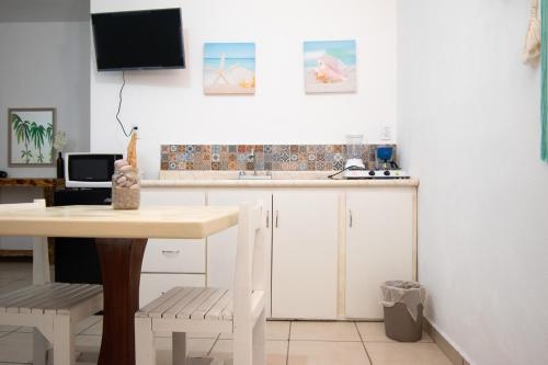 a kitchen with white cabinets and a table and a tv at Isla Venados Renta Vacacional in Mazatlán