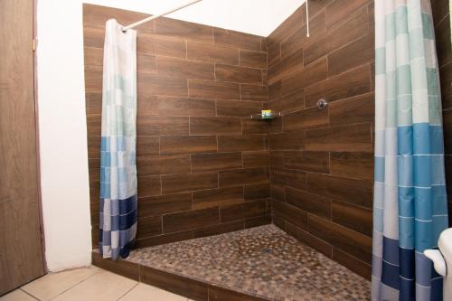 a shower with wooden tiles and a shower curtain at Isla Venados Renta Vacacional in Mazatlán