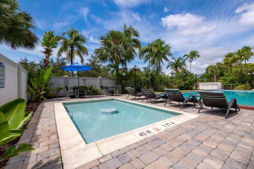 a pool with chairs and a table and an umbrella at Best Western Plus North Miami-Bal Harbour in North Miami