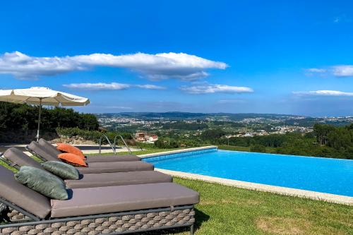 a pool with lounge chairs and an umbrella next to it at The FarmHouse II - Uma quinta deslumbrante in Felgueiras