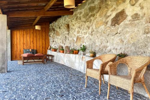 a room with two chairs and a stone wall at The FarmHouse II - Uma quinta deslumbrante in Felgueiras