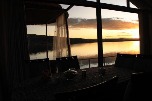 a room with a table with a view of the water at TITICACA JALTAWI LODGE in Puno