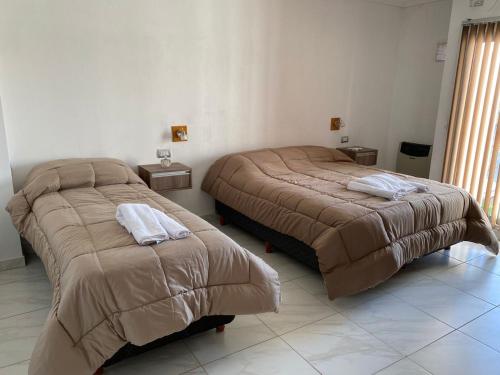 two beds sitting next to each other in a room at Apart Los Algarrobos in Marcos Juárez