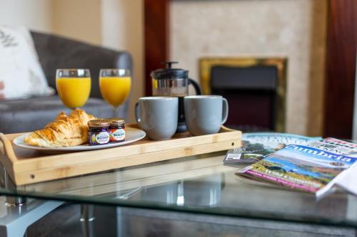 a tray with a plate of food and two glasses of orange juice at Adrian House, near Hospital, easy parking + garden in Carlisle