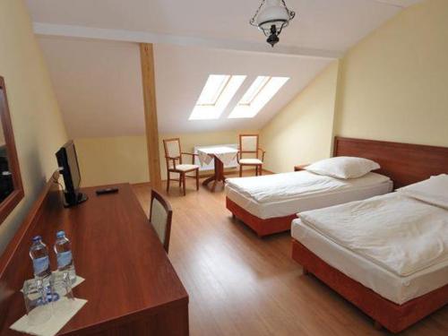 クロチツェにあるZajazd Magdaのベッド2台、テーブルと椅子が備わるホテルルームです。