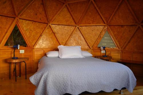 1 dormitorio con 1 cama en una habitación de madera en Arrecife Glamping, en Guatavita