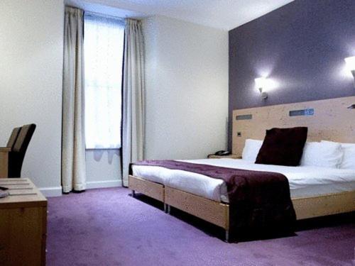 a hotel room with a bed, chair, and nightstand at Artto Hotel in Glasgow
