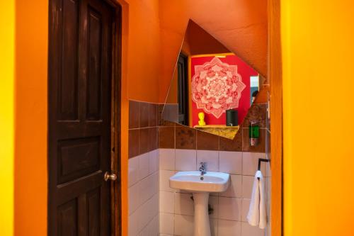 Baño de color naranja con lavabo y espejo en Why Not Hotel, en Antigua Guatemala