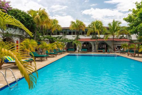 Hotel Mariscal Robledo في سانتا في دي أنتيوكيا: وجود مسبح في المنتجع مع الكراسي والنخيل
