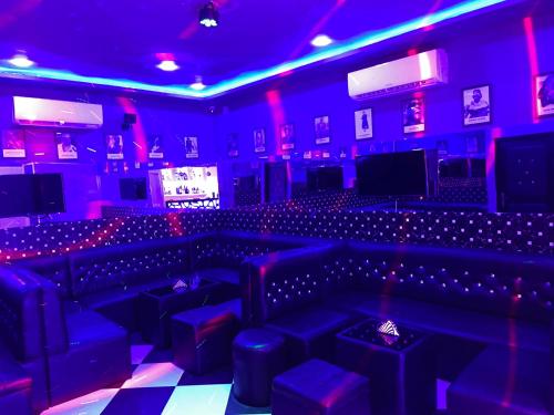 a room with purple lights and a stage with stools at HOTEL LES ARCADES in Abomey-Calavi