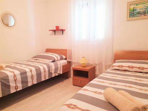 two beds in a small room with a window at Apartments with a parking space Rukavac, Vis - 8496 in Rukavac