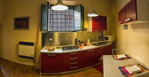 una piccola cucina con armadi rossi e una finestra di Nice apartment on the riverside a Pisa