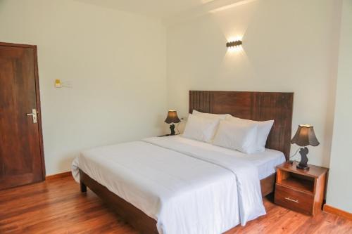 a bedroom with a large white bed with two lamps at Dream Stay Green in Nuwara Eliya