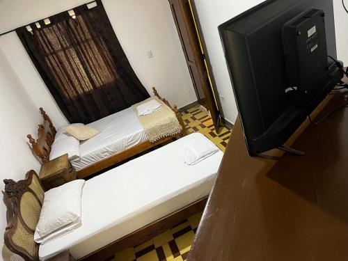 a small room with two beds and a television at Casa Grande in Medellín