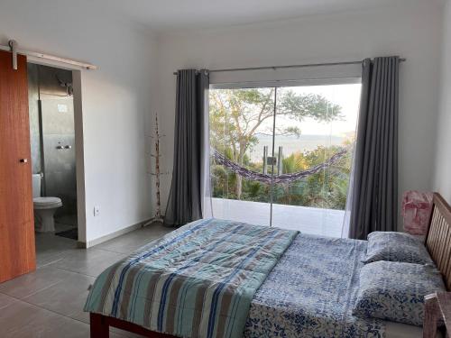 ein Schlafzimmer mit einem Bett und einem großen Fenster in der Unterkunft CASA VAHIANA in Búzios