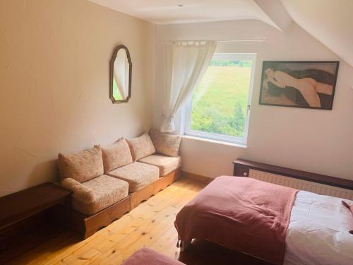 a bedroom with a couch and a bed and a window at Lovely Meadow House in the land of Croix Scaille in Gedinne