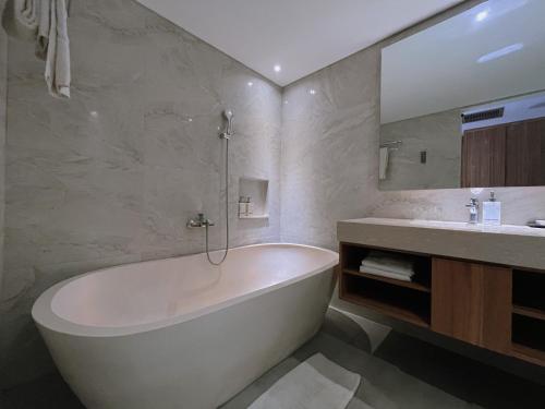 a bathroom with a bath tub and a sink at The Capital Hotel and Resort Seminyak - CHSE Certified in Seminyak