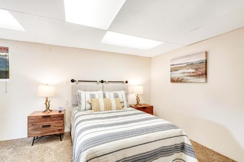 a white bedroom with a bed and two lamps at The Lakefront Treehouse in Shelton