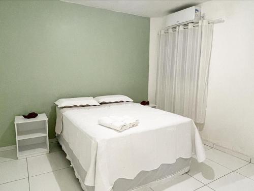 um quarto com uma cama branca e uma parede verde em Casa em Peroba/Maragogi 100m da Praia em Ponta do Mangue