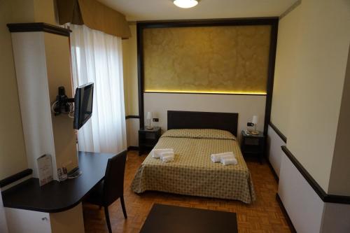 a hotel room with a bed and a desk and a desk at Hotel Astoria in Fidenza