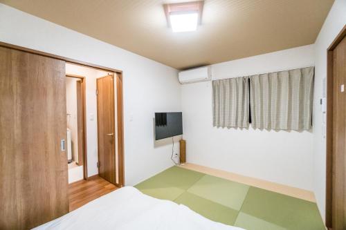 1 dormitorio con 1 cama y TV en la pared en HANASTAY花渓居 · 川（KAWA）, en Osaka