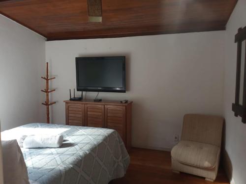 um quarto com uma cama e uma cadeira e uma televisão de ecrã plano em Chalé das Montanhas - Cachoeira particular dentro da hospedagem em Nova Friburgo