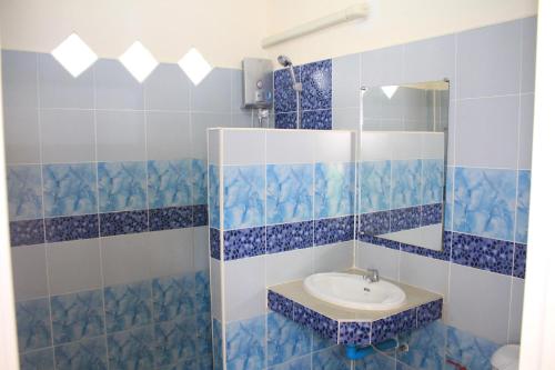 Baño de azulejos azules con lavabo y espejo en Dragon Hut Resort, en Haad Yao