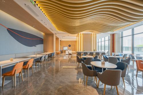 a restaurant with tables and chairs and a ceiling at Holiday Inn Express Huludao Seaview, an IHG Hotel in Huludao