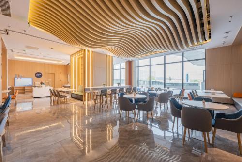 uma sala de jantar com mesas, cadeiras e janelas em Holiday Inn Express Huludao Seaview, an IHG Hotel em Huludao