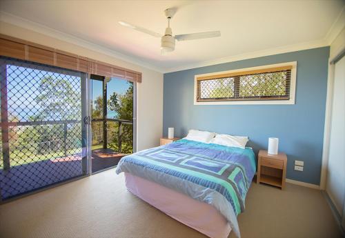 a bedroom with a bed and a sliding glass door at Tangalooma Holiday House in Tangalooma