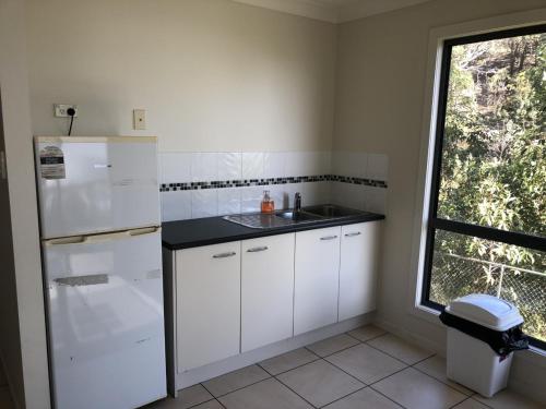a kitchen with white cabinets and a sink and a window at Tangalooma Holiday House in Tangalooma