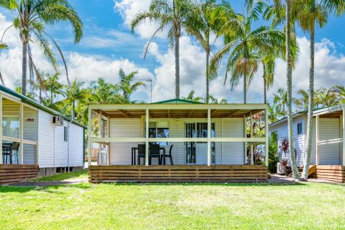 una casa con palmeras delante en Koala Shores Holiday Park, en Lemon Tree Passage