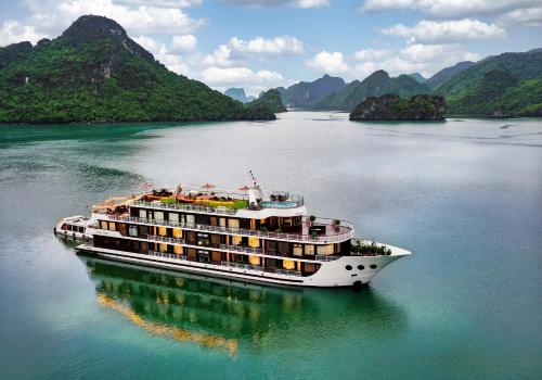a cruise ship in the water with mountains in the background at Dora Cruise by HAG in Ha Long