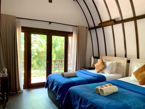 a bedroom with two beds with blue and white sheets at The Yoga Garden in Gili Trawangan