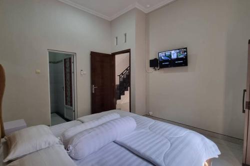 a bedroom with a bed with a tv on the wall at Oemah Wisata RinginSari -Full House, 5 Bed Rooms- in Kalasan
