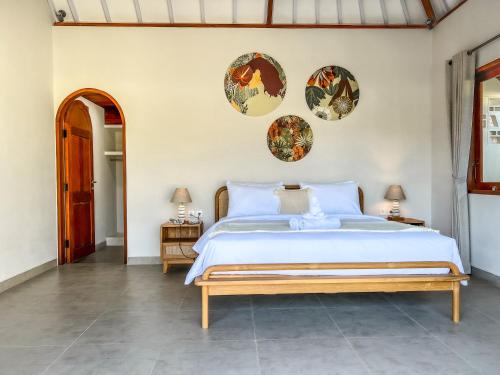 ein Schlafzimmer mit einem großen Bett und drei Platten an der Wand in der Unterkunft Moana Villa & Suites Bingin in Uluwatu