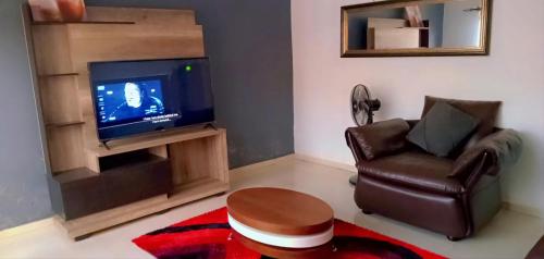 sala de estar con silla y TV en Fully Furnished Apartment in Chililabombwe en Chililabombwe