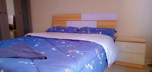 a bed with a blue comforter and a wooden headboard at Fully Furnished Apartment in Chililabombwe in Chililabombwe